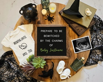May include: A wooden board with a black letter board that reads "Prepare to be Bewitched by the Charms of Baby Lastname". There is a black cauldron, a witch's hat, a baby onesie with a bat and the text "Brewing Until April 20XX", a black cat, a pair of white booties, a black and white ultrasound image, and other Halloween decorations.
