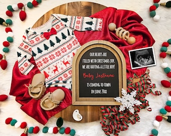 May include: A Christmas-themed baby announcement with a red and green patterned onesie, booties, a wooden rattle, and a framed chalkboard sign that reads "Our hearts are filled with Christmas joy. We are having a little boy! Baby Lastname is coming to town in June 20XX".