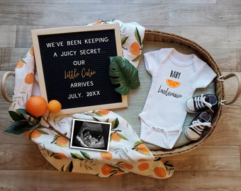 May include: A white onesie with an orange slice graphic and the text "BABY Lastname". A letter board with the text "WE'VE BEEN KEEPING A JUICY SECRET... OUR Little Cutie ARRIVES JULY, 20XX". A black and white ultrasound image. A white and orange patterned blanket.