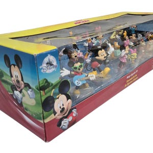 May include: A boxed set of Disney Mickey Mouse figurines. The box features Mickey Mouse graphics and a clear plastic window showcasing the figurines. The set includes various characters in colorful outfits, with Mickey playing a guitar.