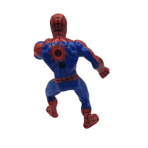 May include: A plastic Spider-Man action figure, viewed from the back, in a dynamic pose. The figure is primarily blue with red accents on the head, hands, and feet. The back features a red spider emblem. The figure is on a white background.