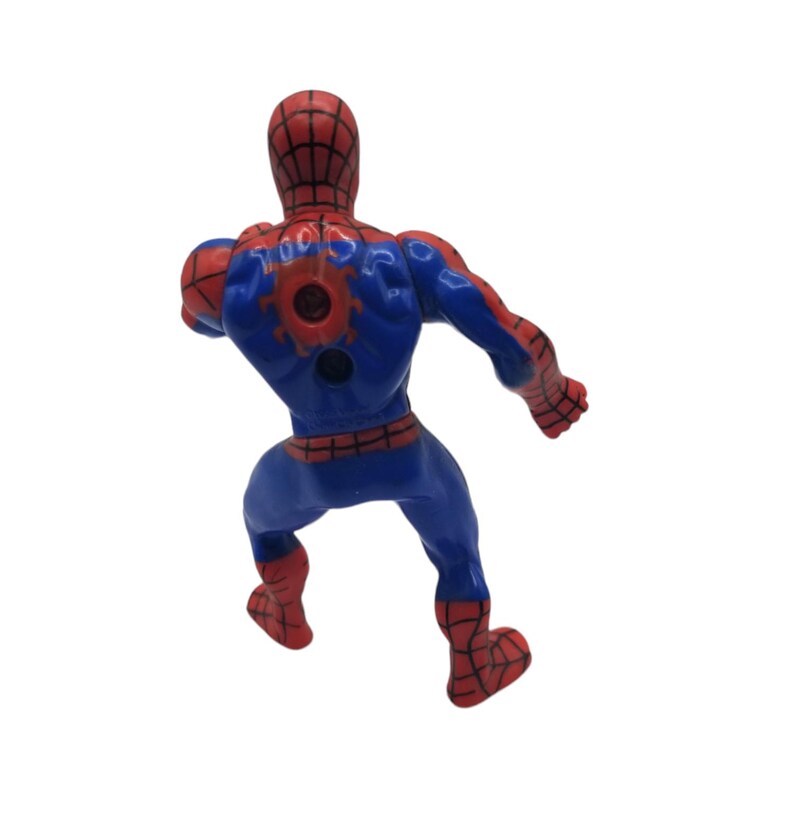 May include: A plastic Spider-Man action figure, viewed from the back, in a dynamic pose. The figure is primarily blue with red accents on the head, hands, and feet. The back features a red spider emblem. The figure is on a white background.