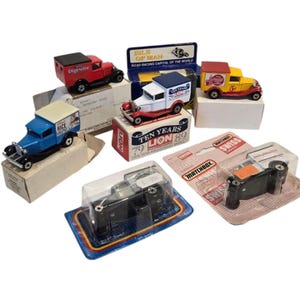 Puede incluir: Una colección de camiones de juguete Matchbox vintage en varios colores, incluyendo rojo, azul, blanco y amarillo. Algunos camiones están en su embalaje original, con texto como "Digestive" y "Rice Krispies" visibles. La colección incluye un modelo aniversario "Ten Years Lion 89".