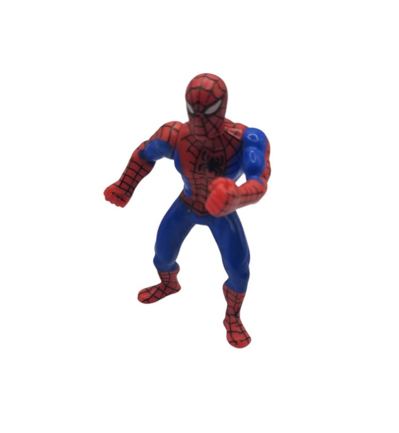 May include: A small Spider-Man action figure in a dynamic pose. The figure is predominantly red and blue, with a detailed web pattern on the red sections. The figure has a black spider emblem on the chest and is standing on a white background.