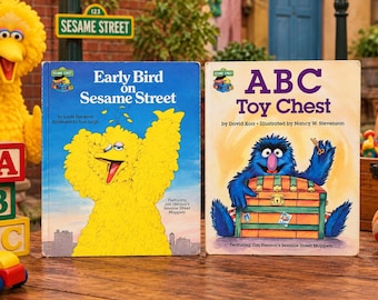 May include: Two Sesame Street children's books titled Early Bird on Sesame Street and ABC Toy Chest. The first book features a large yellow bird character, while the second shows a blue furry monster holding a key over a wooden treasure chest.