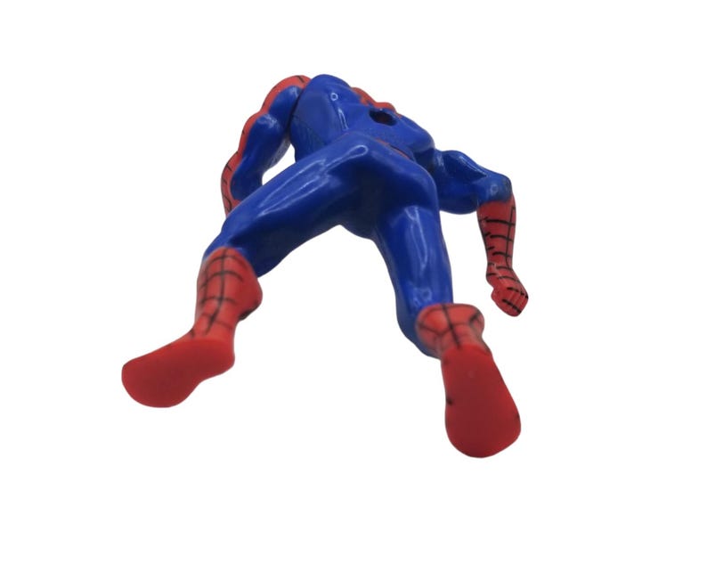 May include: A blue and red Spider-Man action figure, viewed from the back. The figure is in a dynamic pose, with its arms and legs extended. The costume is primarily blue with red accents on the gloves, boots, and mask.