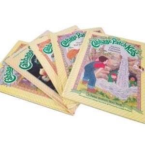 Könnte beinhalten: Ein Stapel Vintage-Bücher der Cabbage Patch Kids. Die Cover zeigen Illustrationen von Kindern und das Cabbage Patch Kids-Logo. Die Bücher sind in gutem Zustand, mit vergilbtem Papier.