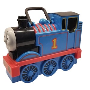 May include: A blue and red toy train with the number 1 on the side. The train has a black handle on top and a smiling face on the front. The wheels are blue.