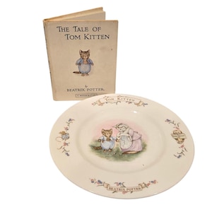 Puede incluir: Una copia vintage de "The Tale of Tom Kitten" de Beatrix Potter y un plato a juego. El libro y el plato presentan ilustraciones de un gato con un atuendo azul. El plato tiene un borde rosa y verde.