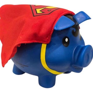 Può includere: Un salvadanaio blu con un mantello rosso con il logo giallo di Superman. Il salvadanaio ha orecchie blu, una striscia gialla attorno al corpo e dettagli neri. Un oggetto divertente e decorativo per risparmiare.