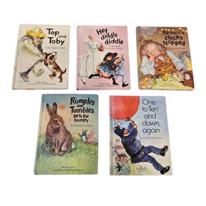 Può includere: Cinque libri per bambini vintage con illustrazioni colorate. I titoli includono "Top and Toby", "Hey Diddle Diddle", "The Day the Clocks Stopped", "Rumples and Tumbles" e "One to Ten and Down Again". I libri sono disposti su una superficie bianca.
