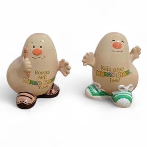 Puede incluir: Dos figuras caprichosas con un cuerpo beige en forma de huevo, brazos pequeños y piernas. Uno sostiene un lápiz y el otro tiene los brazos levantados. El texto en las figuras dice "Bosses are Human Beans Too!" y "Kids are Human Beans Too!". Las figuras tienen caras pintadas y usan zapatos.