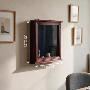 May include: A dark wood shadow box display case with a glass front and a dark interior. The frame features a tiered molding design. The display case measures 12 inches by 12 inches as indicated by the white dimension arrows on the image.