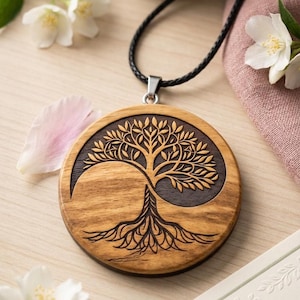 May include: A circular wooden pendant featuring a laser-engraved tree of life design that forms a yin and yang shape. The pendant is suspended from a black cord and displays a natural wood grain finish with contrasting dark and light wood tones.