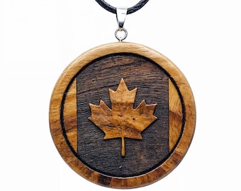 Pode incluir: Um pingente redondo de madeira com um design de bandeira canadense esculpido. O pingente apresenta uma folha de bordo no centro, cercada por uma moldura de madeira marrom escura.