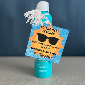 May include: A yellow sun with sunglasses and the text "To the Best Teacher" and "Hope your summer is full of S.P.F! Sunshine, Peace & Fun Love. Theodore" on a white card. The card is placed on top of a blue sunscreen bottle.