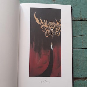 Könnte beinhalten: Eine offene Buchseite mit einer vertikalen Illustration, die einen schwarzen Hintergrund, einen roten unteren Bereich und eine goldfarbene, abstrakte Blumenfigur mit Gesicht zeigt. Unter dem Bild steht der Text: La Fleur Étrange.