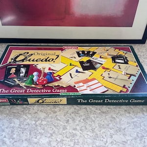 Könnte beinhalten: Eine rechteckige Brettspielschachtel für Cluedo, The Great Detective Game von Waddingtons. Der Deckel zeigt einen gelben Grundriss eines Herrenhauses, bunte Spielfiguren, Miniatur-Waffenteile und eine Lupe auf einem dunkelroten Hintergrund.