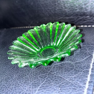 以下が含まれることがあります： 縁がギザギザになった小さな緑色のガラス製の皿。皿は花の形をしていて、中央が少し盛り上がっている