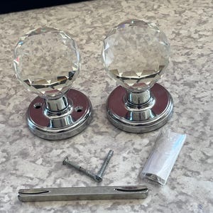 Tiradores de puerta de embutir de cristal facetado de Tahari Home con base de cromo pulido y diseño de diamante.