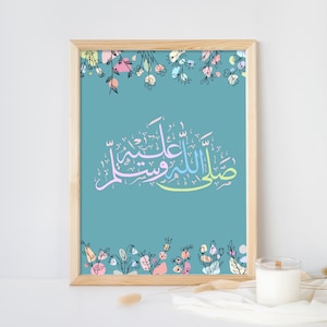 Puede incluir: Una impresión enmarcada azul turquesa con un borde floral y caligrafía árabe en colores pastel. La caligrafía dice "Subhanallah wa bihamdihi, Subhanallahil Azeem".