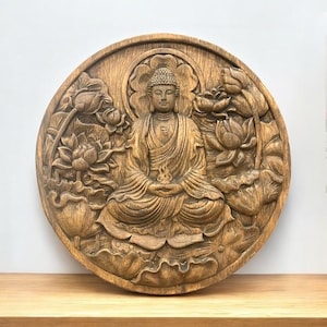 Puede incluir: Talla en relieve de madera redonda de un Buda sentado en meditación, rodeado de flores de loto. La figura de Buda lleva una túnica tradicional, con las manos en el regazo. La talla es en tonos marrones y beige.