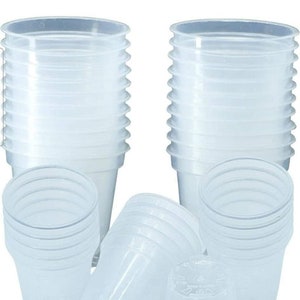 May include: A stack of 10 clear plastic cups, with a few cups laying on their side. The cups are made of a clear, translucent plastic and are stacked on top of each other. The cups are all the same size and shape.