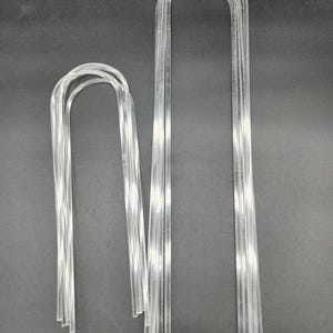 May include: Two sets of clear plastic U-shaped wire hangers. The larger set has 10 hangers and the smaller set has 5 hangers.