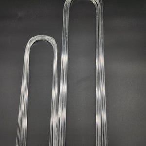 May include: Two sets of clear plastic hangers, one set is larger than the other. The hangers are made of multiple thin strips of plastic.