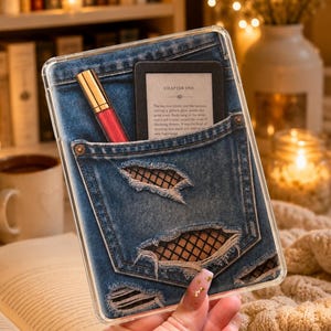 Può includere: Una custodia trasparente per telefono con un design a tasca di jeans, con dettagli strappati. Un rossetto rosso e un e-reader nero con il testo "CHAPTER ONE" sono nella tasca.