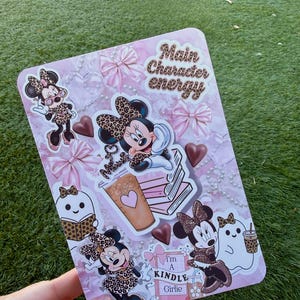 May include: A pink rectangular sticker sheet featuring Minnie Mouse in various poses, wearing leopard print bows and outfits. The sheet includes the text "Main Character energy" and "I'm a Kindle Girlie."