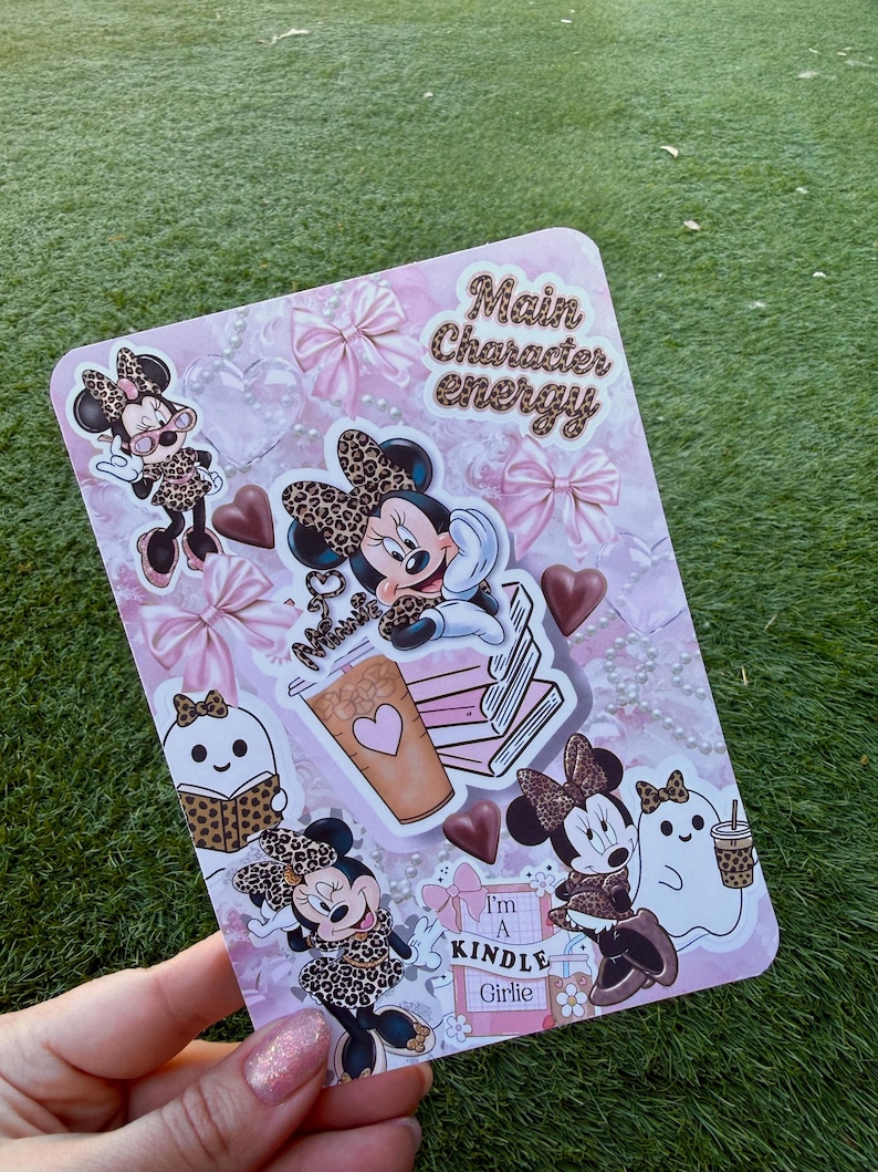 May include: A pink rectangular sticker sheet featuring Minnie Mouse in various poses, wearing leopard print bows and outfits. The sheet includes the text "Main Character energy" and "I'm a Kindle Girlie."