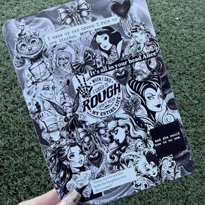 May include: Black and white illustration featuring various fairytale characters and quotes. The design includes images of the Cheshire Cat, Snow White, and other figures, with text that reads "I make my own crown; I rule my own kingdom."