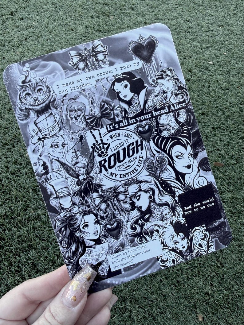 May include: Black and white illustration featuring various fairytale characters and quotes. The design includes images of the Cheshire Cat, Snow White, and other figures, with text that reads "I make my own crown; I rule my own kingdom."