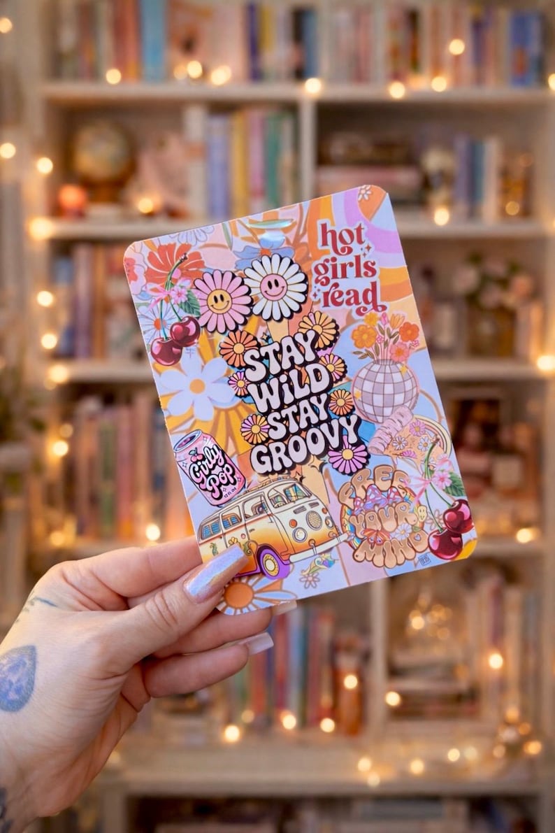 May include: A colorful sticker with a retro design featuring daisies, a VW bus, cherries, and the text "Stay Wild Stay Groovy" and "Hot Girls Read". The sticker has a light pink, orange, and yellow color scheme.