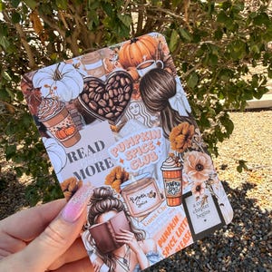 May include: A rectangular sticker sheet featuring a collage of autumn-themed illustrations including pumpkins, coffee cups, a heart filled with coffee beans, and two figures reading books. Text includes READ MORE, PUMPKIN SPICE CLUB, and a chapter begins.