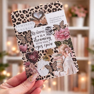 May include: A decorative card with a leopard print border and the words "FEMININE ENERGY" and "READING IS dreaming WITH YOUR eyes open." The card features illustrations of butterflies, hearts, and flowers. A quote is also included.