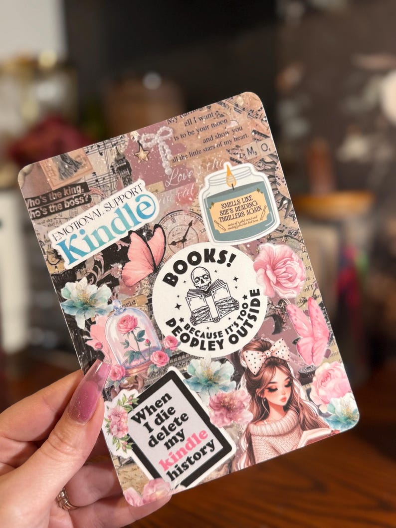 May include: A Kindle case covered in stickers with a floral and book theme. Stickers include the words "Kindle," "Books!", and "When I die delete my kindle history." Other stickers feature a rose in a glass dome, a butterfly, and a girl reading.