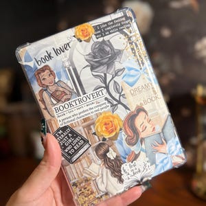 May include: A clear phone case with a collage design. It features illustrations of women reading, roses, and the text "book lover" and "Booktrovert." The case has a gold glitter accent and quotes about reading.