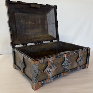 May include: A wooden treasure chest with an open lid. The chest is brown with metal accents and diamond-shaped embellishments. The metal trim has a rusted appearance. The chest is designed to look antique.