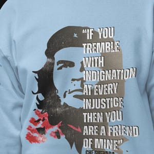 May include: Pale blue sweatshirt with a black and grey graphic of Che Guevara and the quote, "If you tremble with indignation at every injustice then you are a friend of mine." The text is in white.