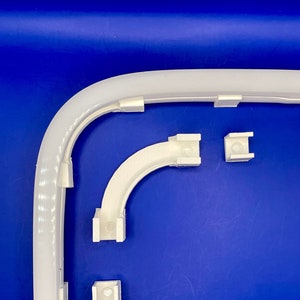 May include: White plastic corner connectors for LED strip lights. The connectors are designed to create a 90-degree angle in the LED strip.