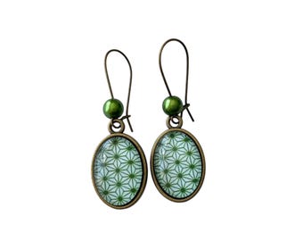 May include: A pair of green and white oval earrings with a geometric pattern. The earrings have a bronze finish and are accented with a green bead.