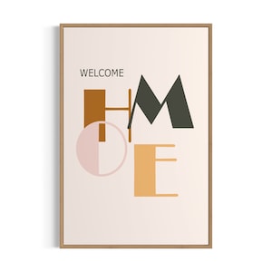 May include: A framed print with the word "WELCOME" at the top and the word "HOME" in stylized, geometric letters in orange, brown, pink, and black on a light beige background.