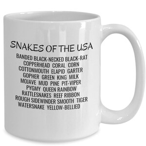 May include: White ceramic mug with a black design that reads "Snakes of the USA" and lists various snake species names.