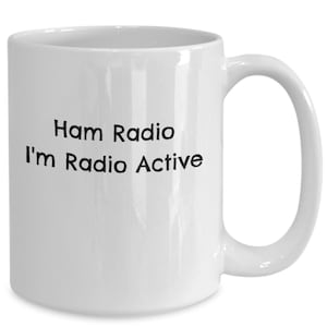 May include: White ceramic coffee mug with black text that reads "Ham Radio I'm Radio Active".
