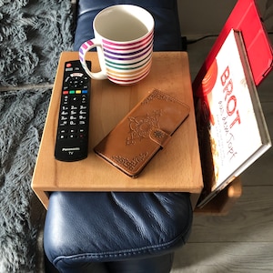 Könnte beinhalten: Ein Holztablett mit einer Fernbedienung, einer braunen Leder-Handyhülle, einer gestreiften Tasse und einem Kochbuch mit dem Titel "Brot aus dem Topf".