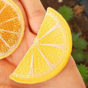 Peut inclure: Deux patchs brodés jaunes en forme de tranches d'orange. Les patchs ont un contour blanc et un design brodé détaillé.