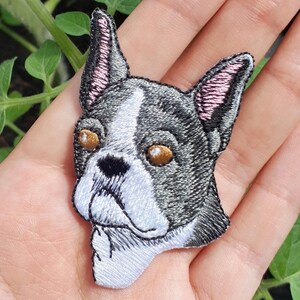 Pode incluir: Etiqueta bordada para passar a ferro de um Bulldogue Francês com pêlo preto, branco e cinzento. O cão tem olhos castanhos e orelhas cor-de-rosa.