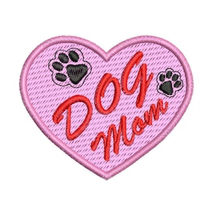 Könnte beinhalten: Rosa Herzförmiger Patch mit dem Text "Dog Mom" in roter Stickerei. Zwei schwarze Pfotenabdrücke sind auf dem Patch gestickt.